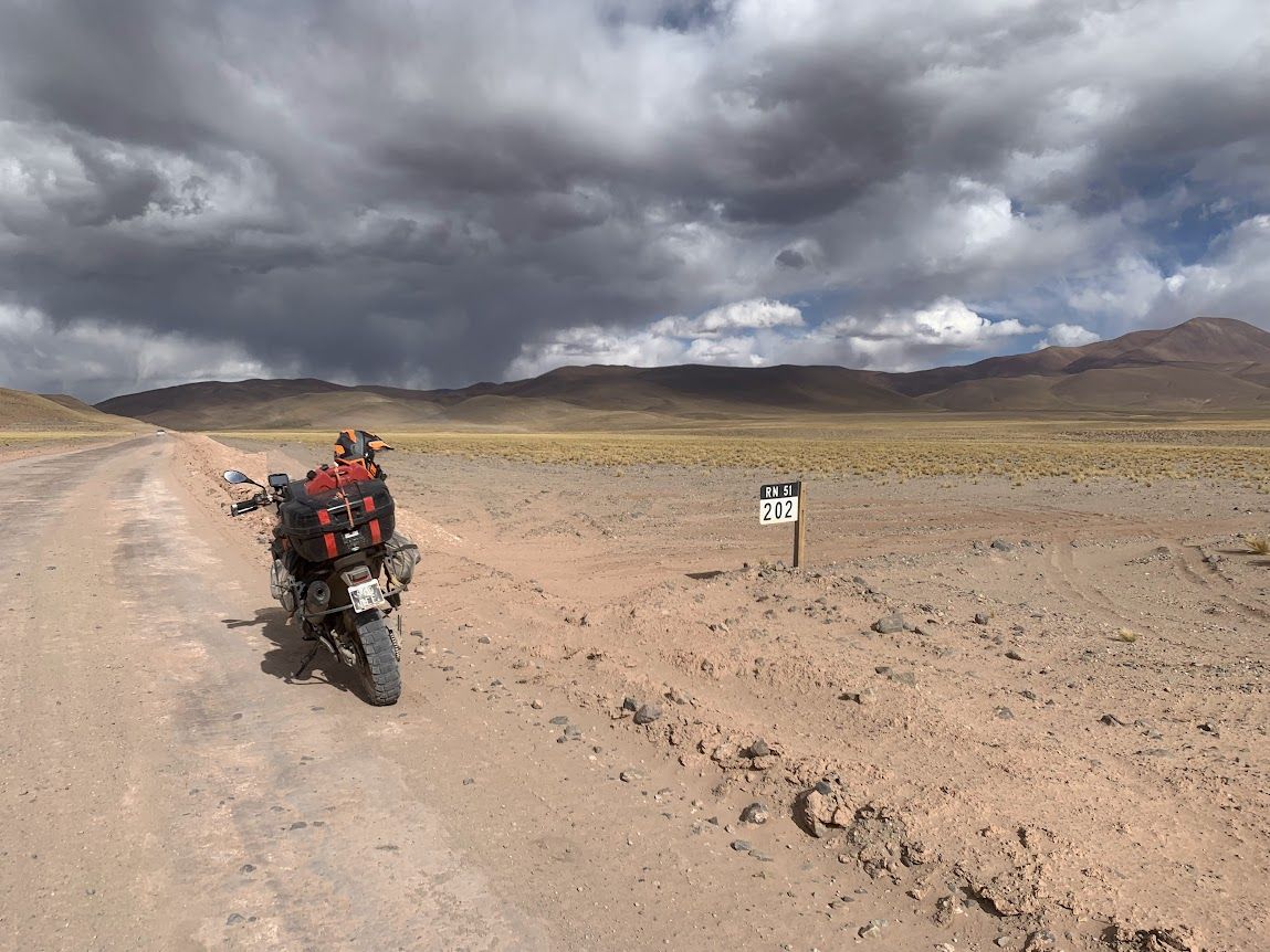 Moto de viaje estacionada junto al mojón de la Ruta Nacional 51, en la Puna